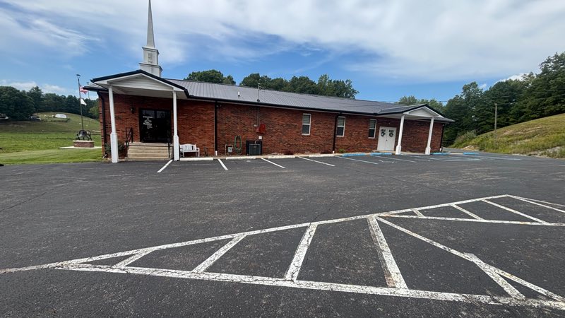 New Beginning Church of the Nazarene on Copley Road: a single-storey red-brick building with a white steeple, a covered entrance porch, and an American flag beside the front steps.